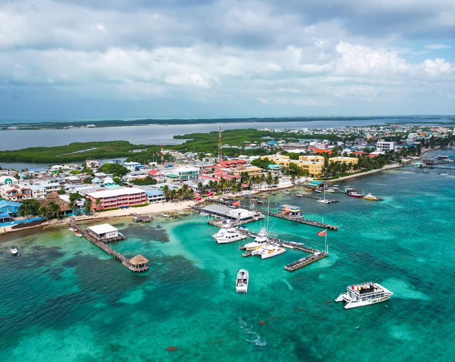 Aerial view of a coastal town with colorful buildings, docks, and boats on turquoise waters.