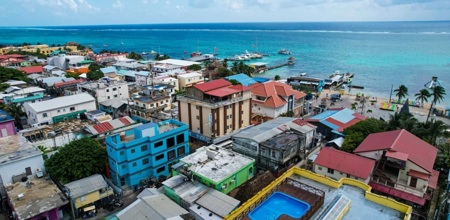 Aerial view of a coastal town with colorful buildings and boats near a turquoise sea.