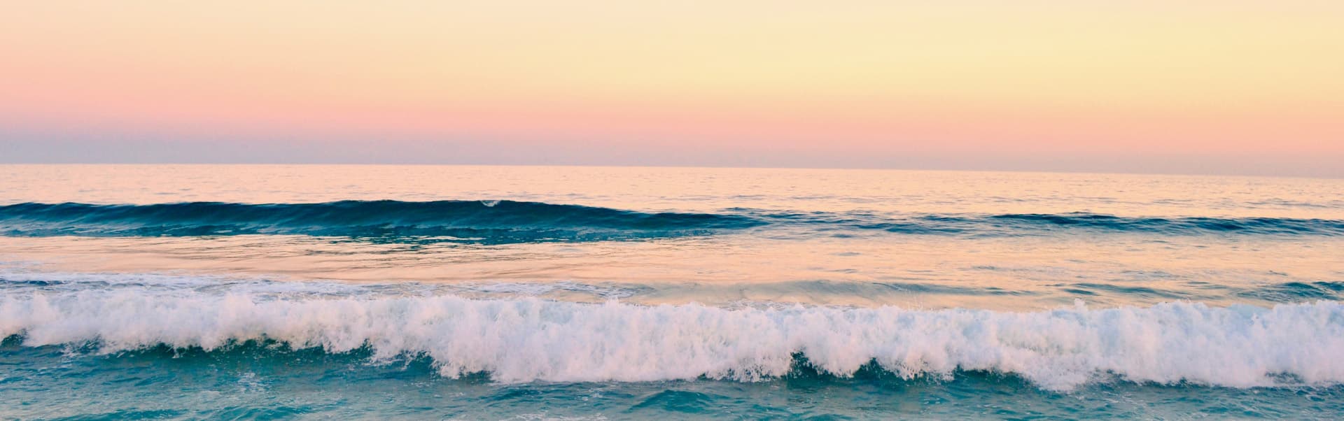 A serene ocean scene with gentle waves under a pastel sunset sky.