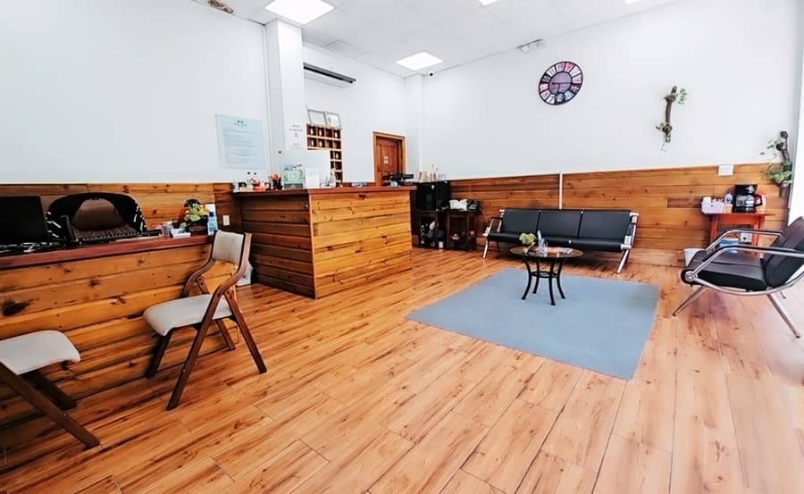 A warmly decorated waiting area with wooden walls, a reception desk, and comfortable seating.